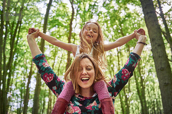 Frau lässt Tochter im Wald auf der Schulter reiten