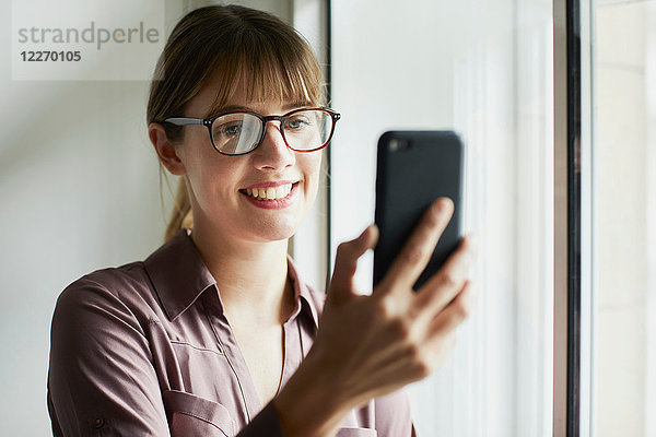 Frau schaut lächelnd auf Smartphone