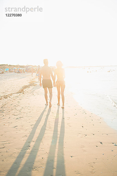 Erwachsenes Paar beim Strandspaziergang  Händchen haltend  Rückansicht