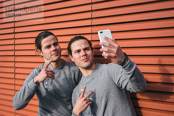 Junge erwachsene männliche Zwillinge machen eine Trainingspause  machen Selfie
