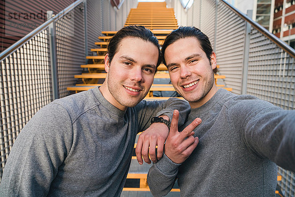 Junge erwachsene männliche Zwillinge trainieren zusammen  Treppenhaus-Selbstporträt