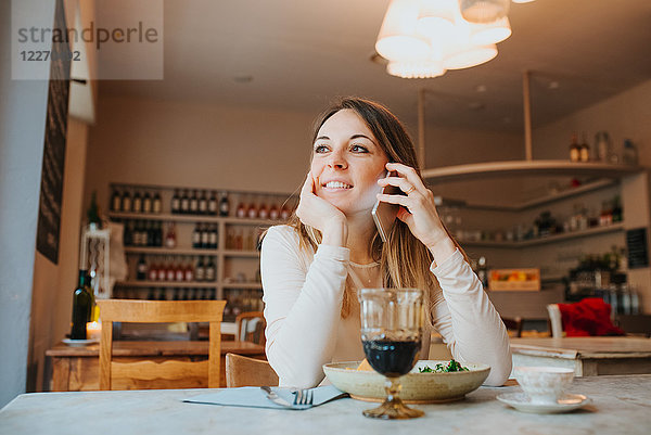 Frau benutzt Handy beim veganen Essen im Restaurant