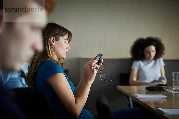 Geschäftsfrau im Büro textet auf Smartphone