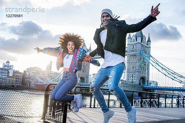 Junges Paar im Freien  vor Freude hüpfend  Tower Bridge im Hintergrund  London  England  UK