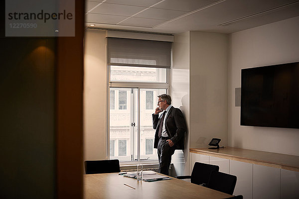 Geschäftsmann im Büro telefoniert auf Smartphone