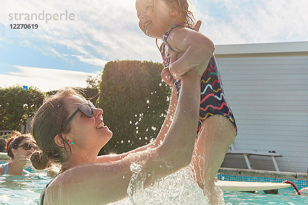 Frau hält Kleinkind-Tochter im Schwimmbad