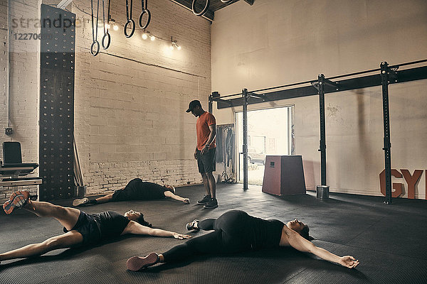 Gymnastiklehrer  der Personen beaufsichtigt  die im Fitnessstudio Bodenübungen machen
