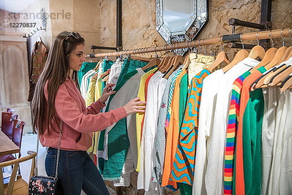 Junge Frau beim Einkaufen  schaut sich im Laden Kleider auf der Schiene an