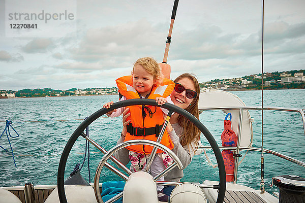 Frau steuert Yacht mit Kleinkind Tochter  Portrait  Devon  UK