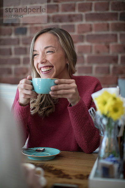 Frau sitzt im Café  trinkt Kaffee  lächelt