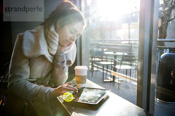 Junges Mädchen sitzt im Café und benutzt ein digitales Tablet  London  England  UK