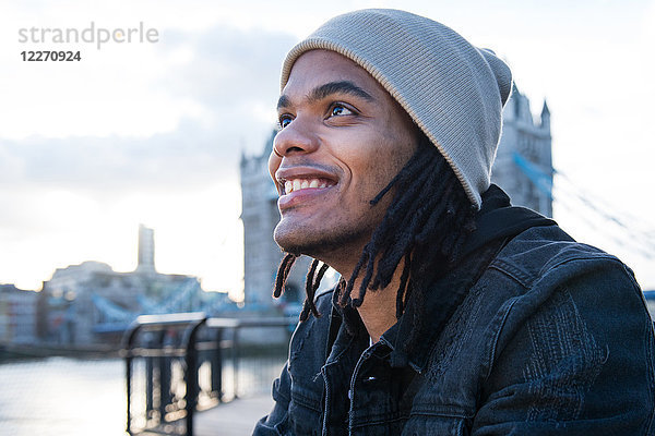 Porträt eines jungen Mannes  der im Freien sitzt und lächelt  London  England  UK