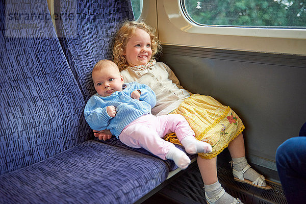 Weibliches Kleinkind sitzt mit kleiner Schwester im Zug