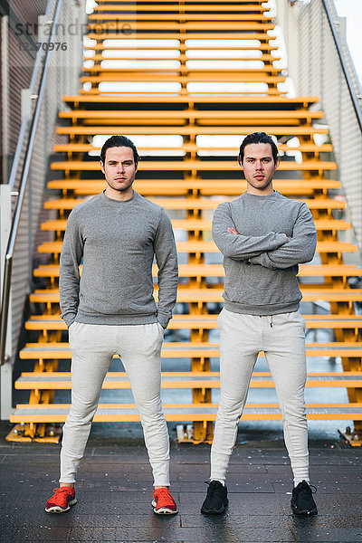 Junge erwachsene männliche Zwillinge  die zusammen trainieren  Treppenhaus-Portrait
