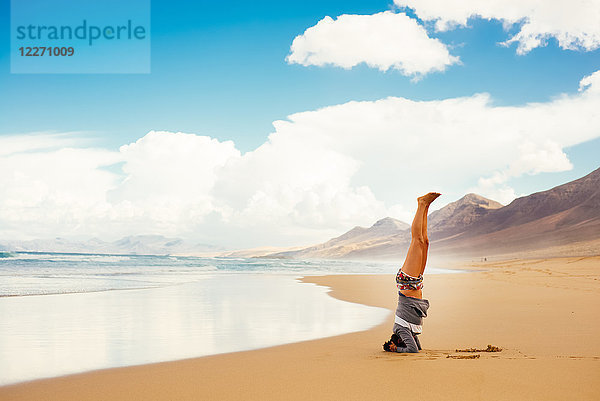 Frau macht Kopfstand am Strand  Corralejo  Fuerteventura  Kanarische Inseln