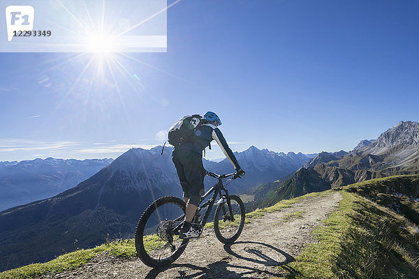 Mountainbiker beim Bergauffahren in alpiner Landschaft