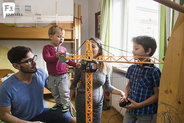 Zwei Brüder und ihre Eltern spielen mit einem Spielzeugkran  München  Deutschland