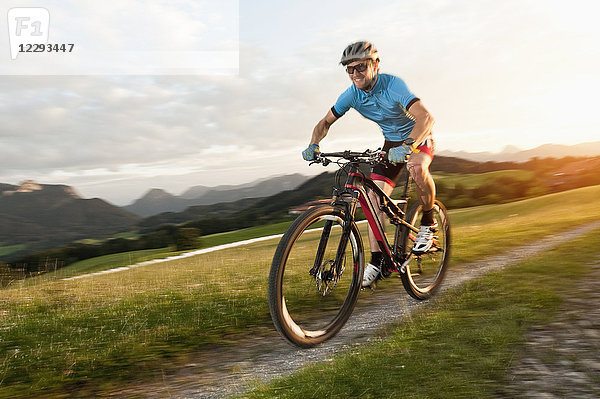 Mountainbiker reitet bei Sonnenuntergang in den Alpen