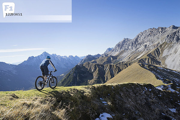 Mountainbiker beim Bergauffahren in alpiner Landschaft