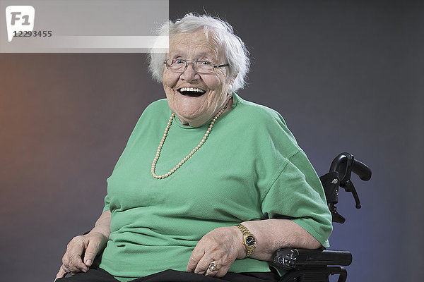 Porträt einer älteren Frau im Rollstuhl sitzend und lachend