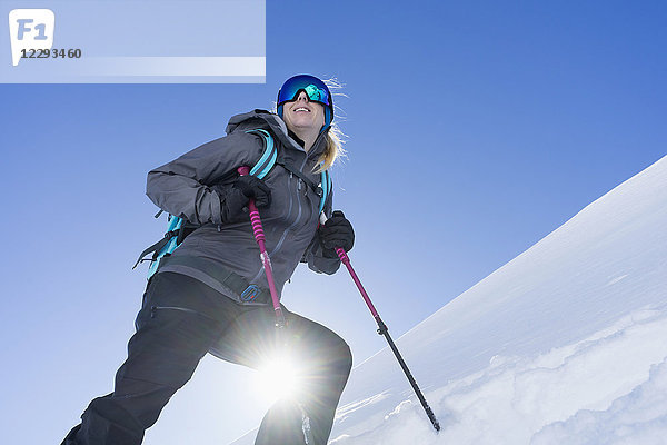 Niedriger Blickwinkel einer Frau beim Skifahren unter hellem Sonnenlicht
