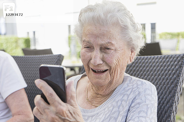 Ältere Frau lächelt und benutzt ein Smartphone