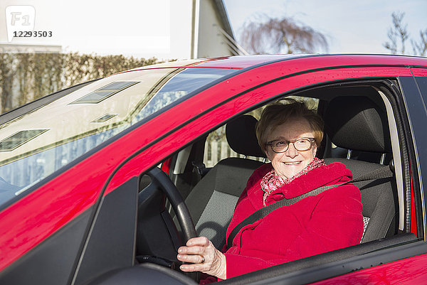 Glückliche alte Frau am Steuer eines Autos