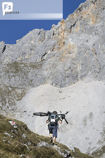 Mountainbiker trägt Fahrrad auf den Schultern