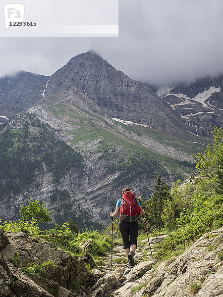 Frau beim Wandern in den Hochpyrenäen auf einem Singletrail mit Blick auf den Cirque de Gavarnie  Frankreich