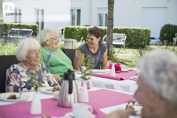 Ältere Frauen mit Krankenschwester am Frühstückstisch