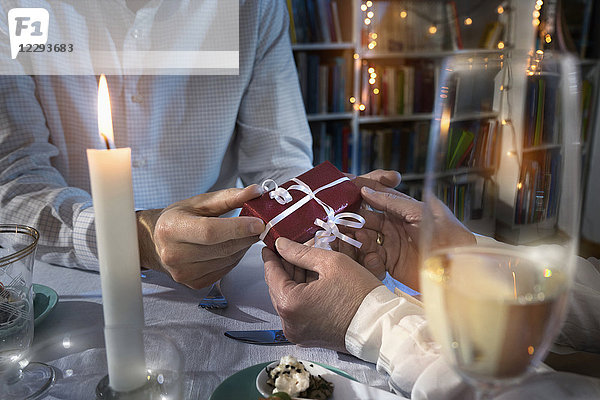 Romantisches Paar tauscht beim Candlelight-Dinner Geschenke aus
