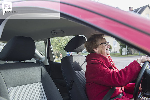 Glückliche alte Frau am Steuer eines Autos