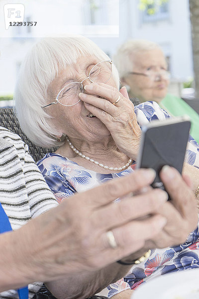 Ältere Frau schaut auf ihr Smartphone und lacht