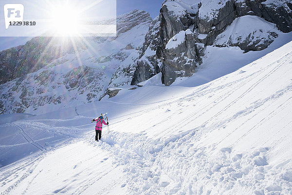 Frau trägt ihre Ski und geht im Schnee