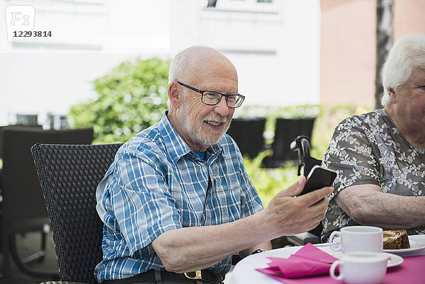 Älterer Mann benutzt Smartphone am Frühstückstisch