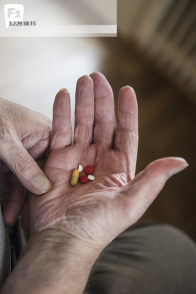 Nahaufnahme eines älteren Mannes  der Tabletten in der Hand hält