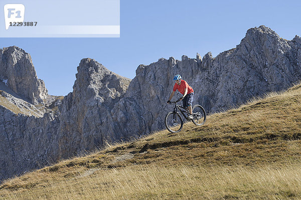 Mountainbiker fährt in alpiner Landschaft bergab