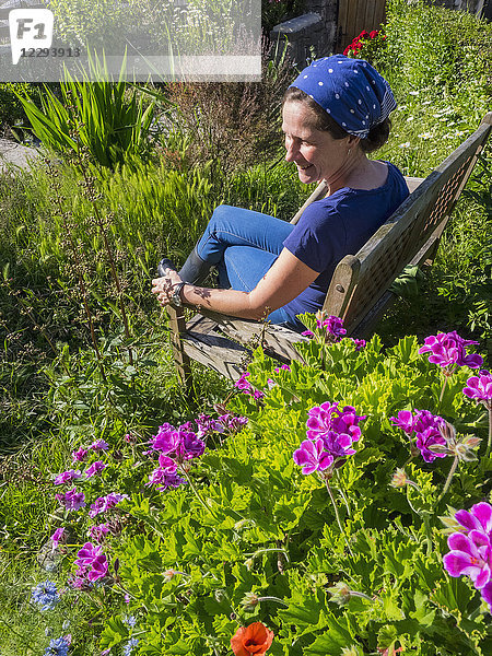 Frau auf Holzbank im Garten sitzend