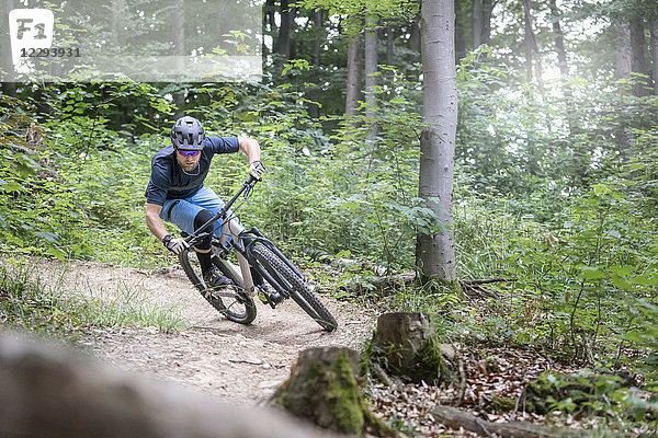 Mountainbiker fährt auf einem Singletrail im Wald bergab