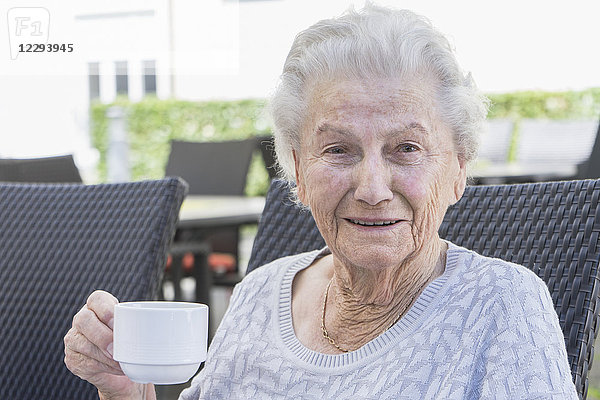 Porträt einer älteren Frau beim Kaffee trinken