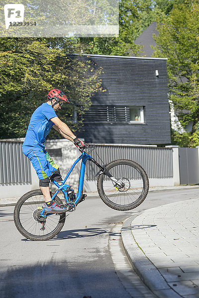 Mann macht einen Wheelie mit Mountainbike