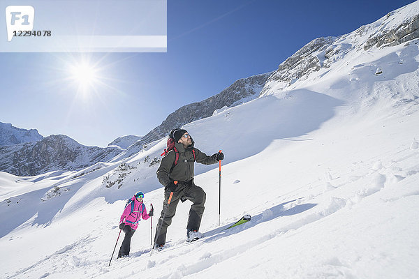 Skifahrer  die im hellen Sonnenlicht die Schneeberge erklimmen
