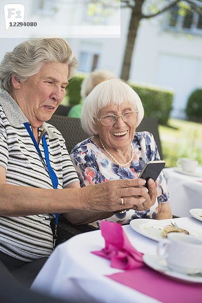 Ältere Frauen lachen und schauen auf ihr Smartphone