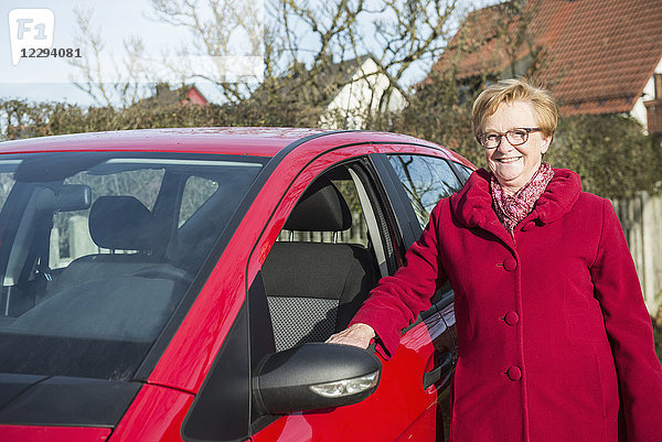 Porträt einer alten Frau  die neben einem Auto steht