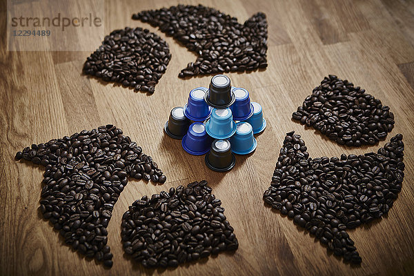 Kaffeebohnen  die ein Recycling-Symbol um Plastik-Kaffeepads bilden