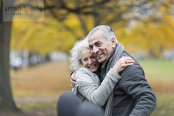 Fröhliches Seniorenpaar beim Umarmen im Herbstpark