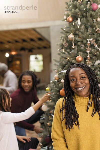 Portrait lächelnde Mutter schmückt Weihnachtsbaum mit Kindern