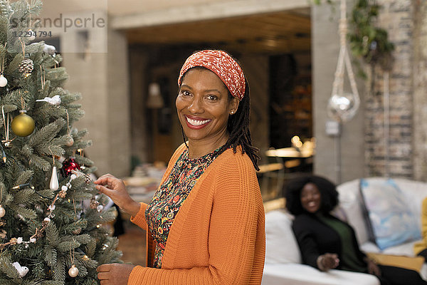 Portrait lächelnde  selbstbewusste Frau schmückt Weihnachtsbaum