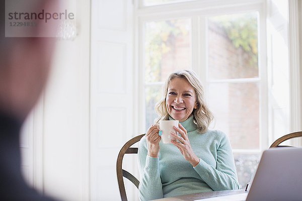 Lächelnde reife Frau trinkt Tee  spricht mit Mann