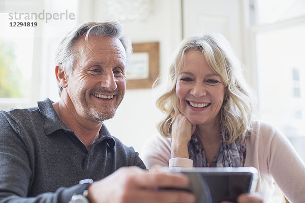 Lächelndes reifes Paar  das ein Smartphone benutzt